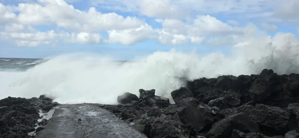 Vague se brisant violemment sur les rochers noirs du port du Baril