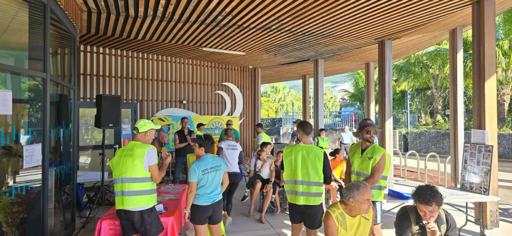 Bénévoles en gilets jaunes sous le préau du Centre aquatique Teddy Hoareau