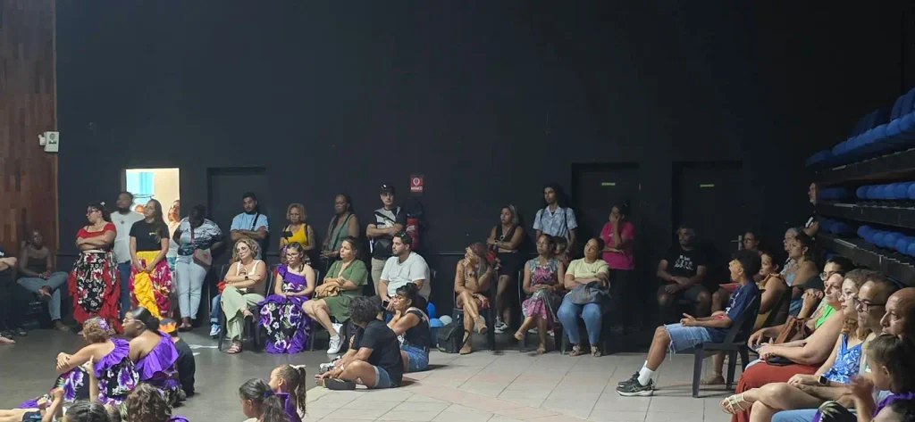 Public assis et debout regardant le spectacle, danseuses au premier plan