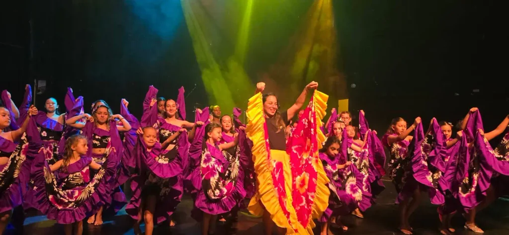 Groupe de danseuses en tenues rose autour d'une danseuse en jupe jaune
