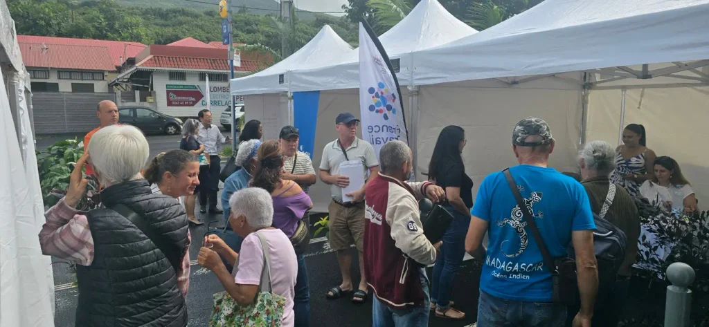 Habitants échangeant devant les tentes des partenaires, drapeau France Travail