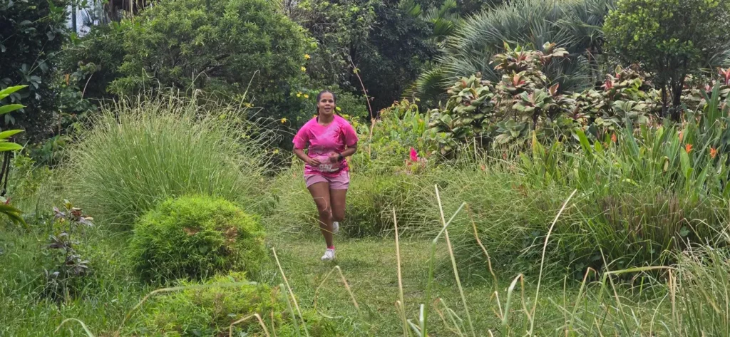 Une coureuse en rose avance sur un sentier bordé de végétation