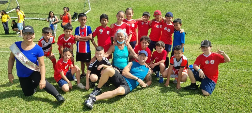 Photo de groupe d'enfants en rouge et de seniors allongés sur l'herbe avec le maire