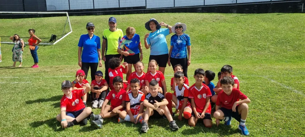 Enfants en maillot rouge et seniors alignés sur la pelouse du stade